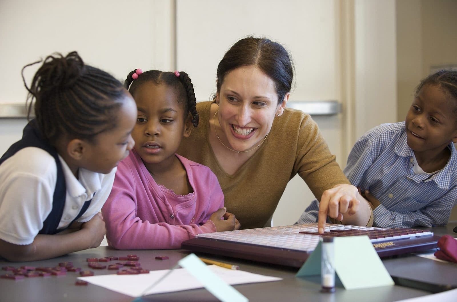 A teacher working with a small group of young students at a table